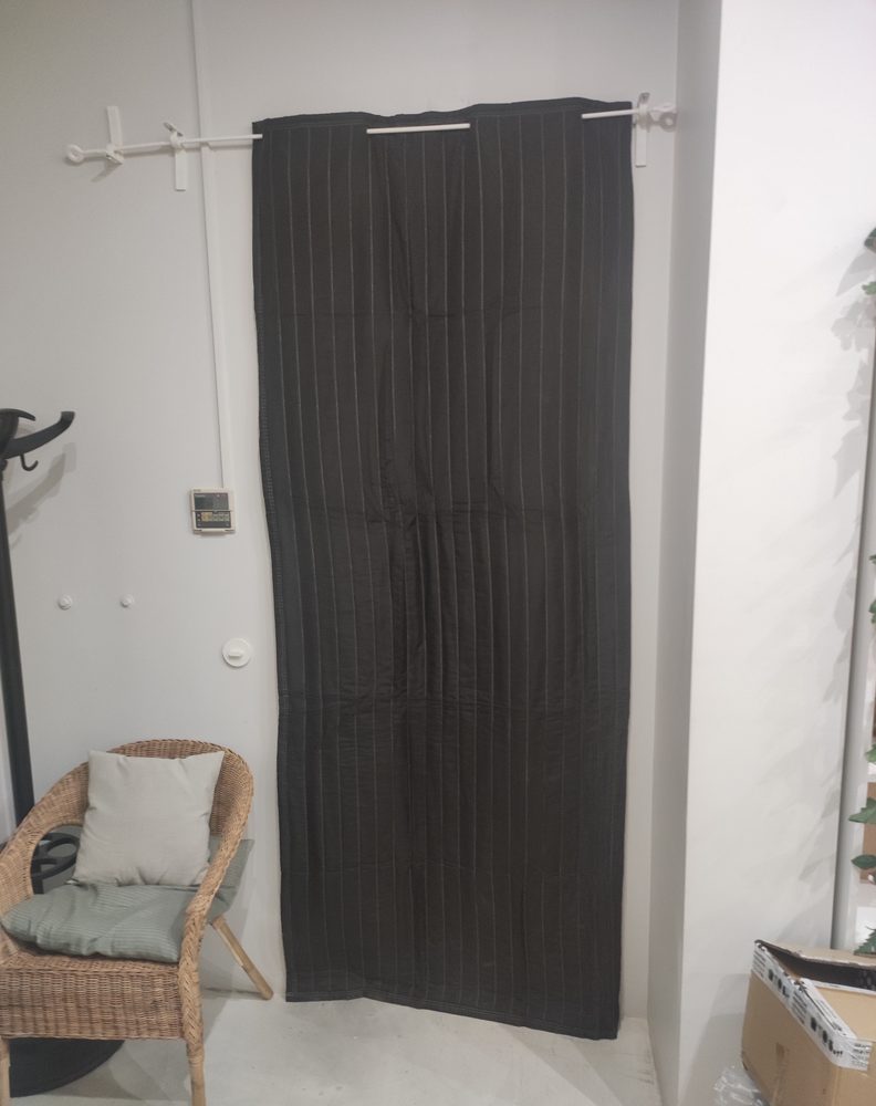 Couverture de porte DNC-B noire suspendue à une tringle devant une porte