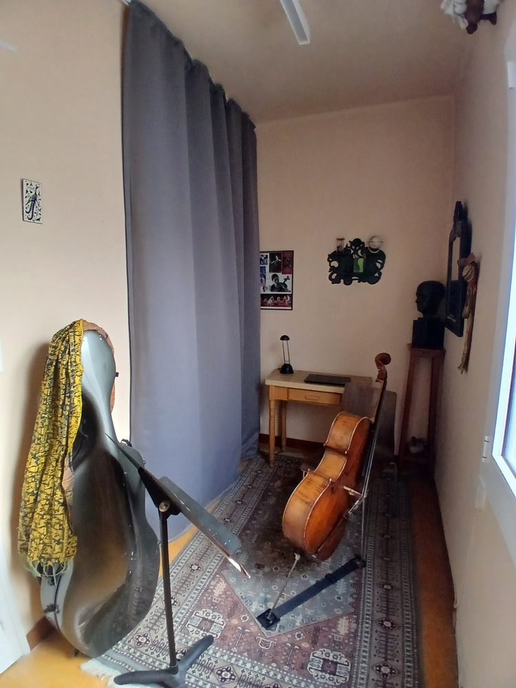 Un rideau gris sépare un couloir utilisé comme salle de répétition de violoncelle