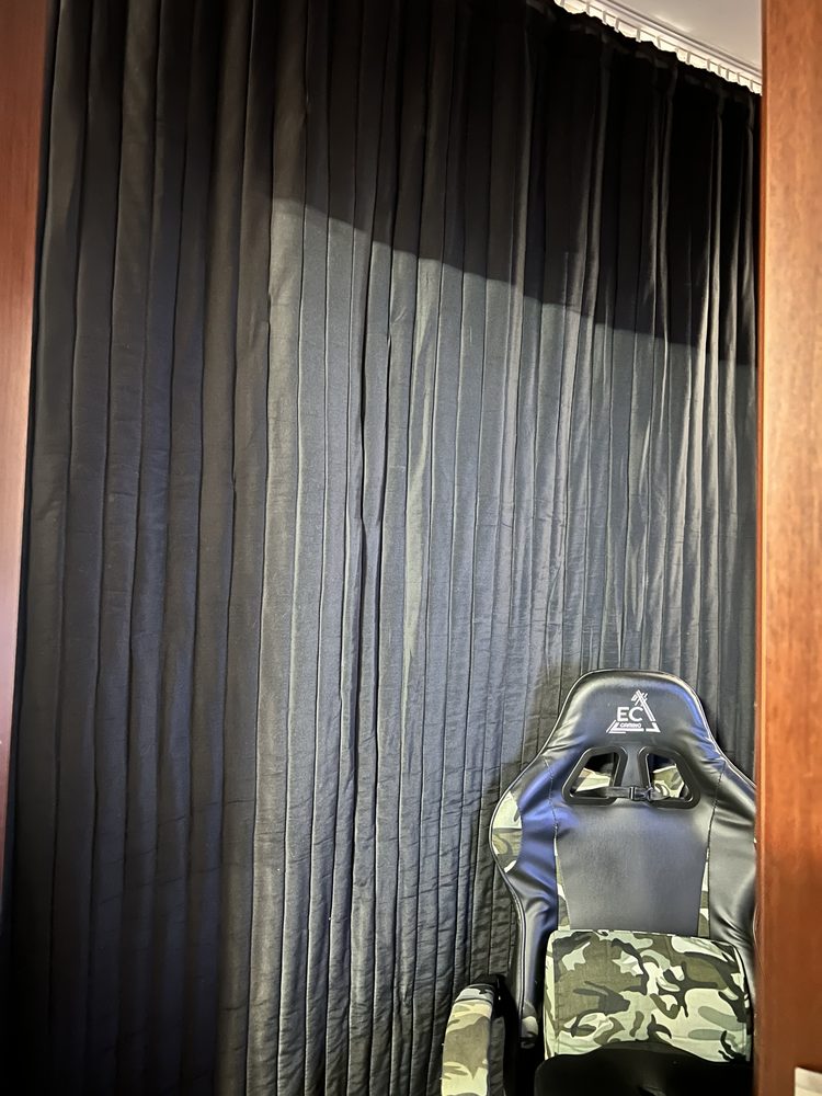 Rideaux sombres sur tout un mur derrière un fauteuil de gaming
