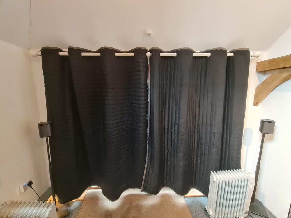 Rideaux acoustiques noirs suspendus avec des plis entre des enceintes