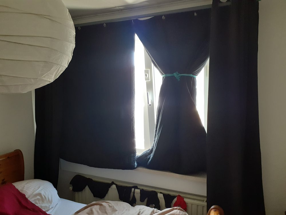Couvertures acoustiques noires en rideau devant la fenêtre d’une chambre
