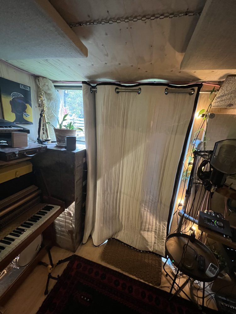 Couverture acoustique devant la fenêtre d’un home studio derrière un piano